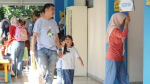 Ayah dan anak bergandengan tangan memasuki ruang kegiatan