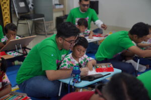 Seorang ayah merangkul anaknya sembari membantu mewarnai