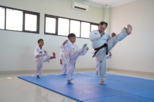 Siswa sedang berlatih teknik tendangan dengan bimbingan dari pelatih berpengalaman