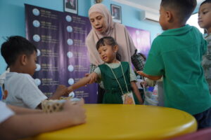 Seorang siswa tampak sedang melihat barang yang dijual dengan bimbingan gurunya