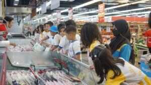 Di depan konter daging, para siswa berjejer rapi sambil melihat mendengarkan penjelasan dari guide