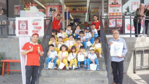 Siswa-siswi Kindy-1 dan beberapa karyawan Superindo berpose dengan ceria di depan gedung