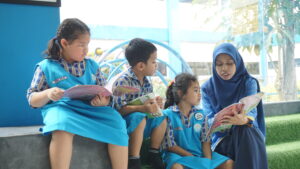 Didampingi seorang guru, siswa tampak menyimak dengan serius isi bukunya