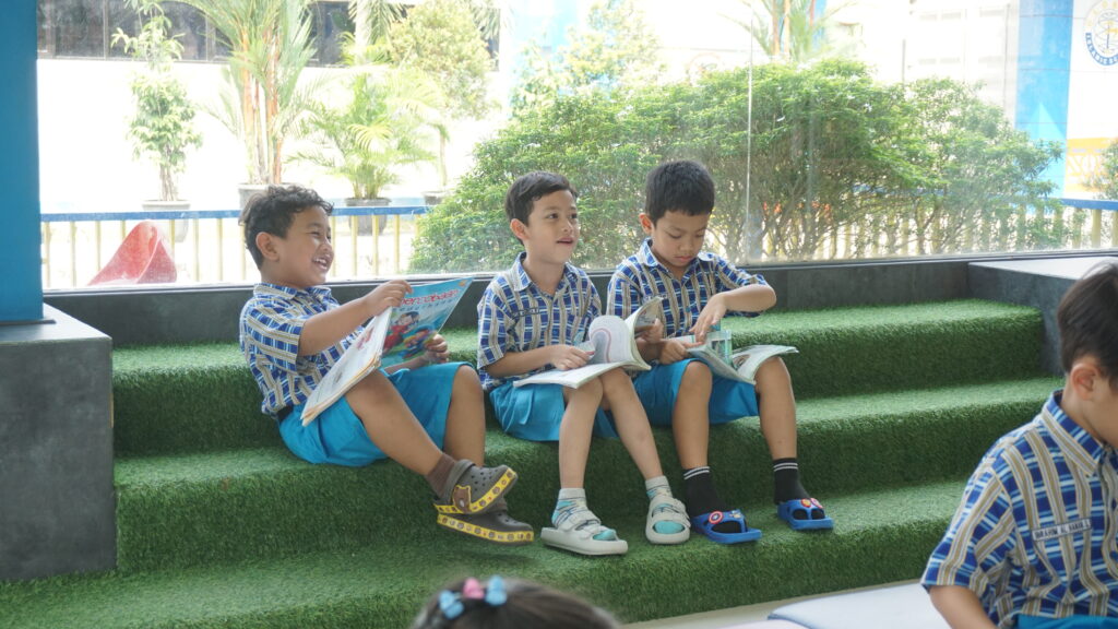Potret keceriaan tiga orang siswa ketika sedang membaca buku