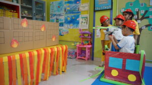 Di Roleplay Area, siswa berpura-pura menjadi pemadam kebakaran yang berusaha memadamkan api sebuah gedung