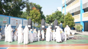 Para siswa berdiri bersisian, mengantre untuk melempar jamrah bergantian