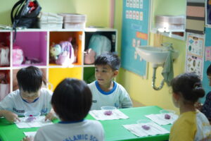 Siswa duduk dalam kelompok kecil dan siap mempraktikkan table manner dengan salad buah di hadapannya
