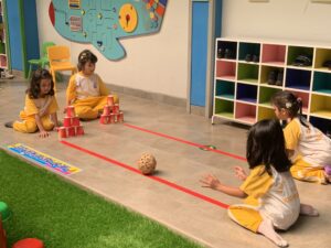Siswa sedang menggelindingkan bola sebagai bagian dari pengembangan motorik kasar