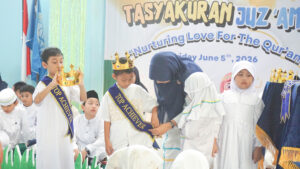 Ms. Lilis memakaikan mahkota dan selempang "Top Achiever" ke salah satu perwakilan siswa